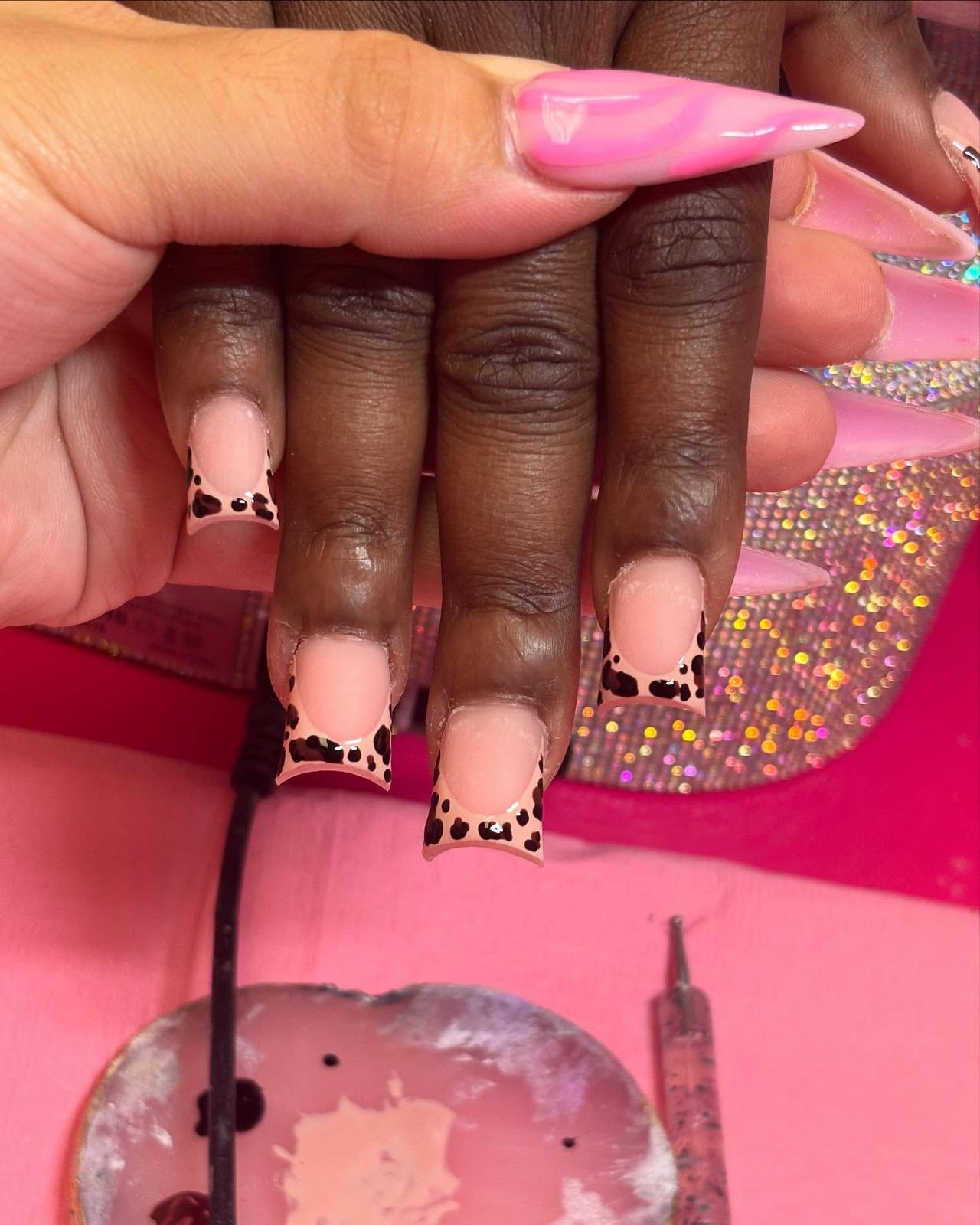 Pink stiletto beside square nude nails with leopard French tips